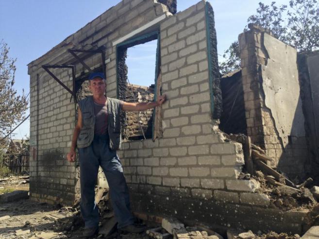 Vladimir, de 50 años, posa junto a su casa destruida en Ilovaisk...