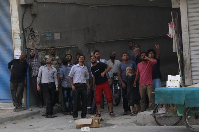 Un grupo de habitantes de Al Raqa observa a los bombarderon que...