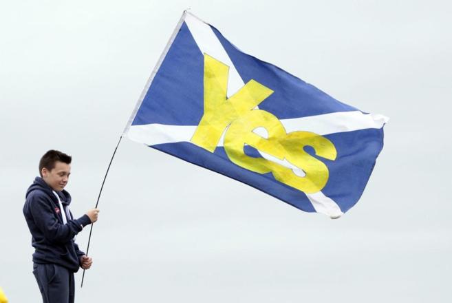 Un joven muestra una bandera escocesa con un 's' escrito...