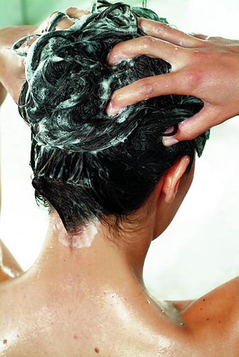 Una mujer se lava el pelo con champú.