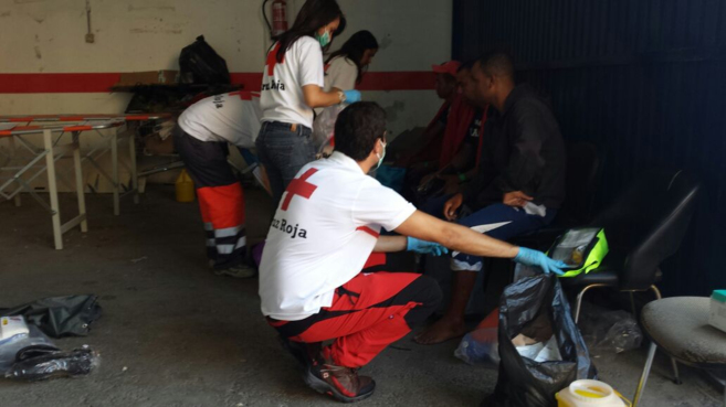 Voluntarios de Cruz Roja atendiendo a varios de los inmigrantes que...