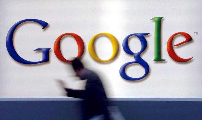 Un hombre camina frente a un cartel de Google