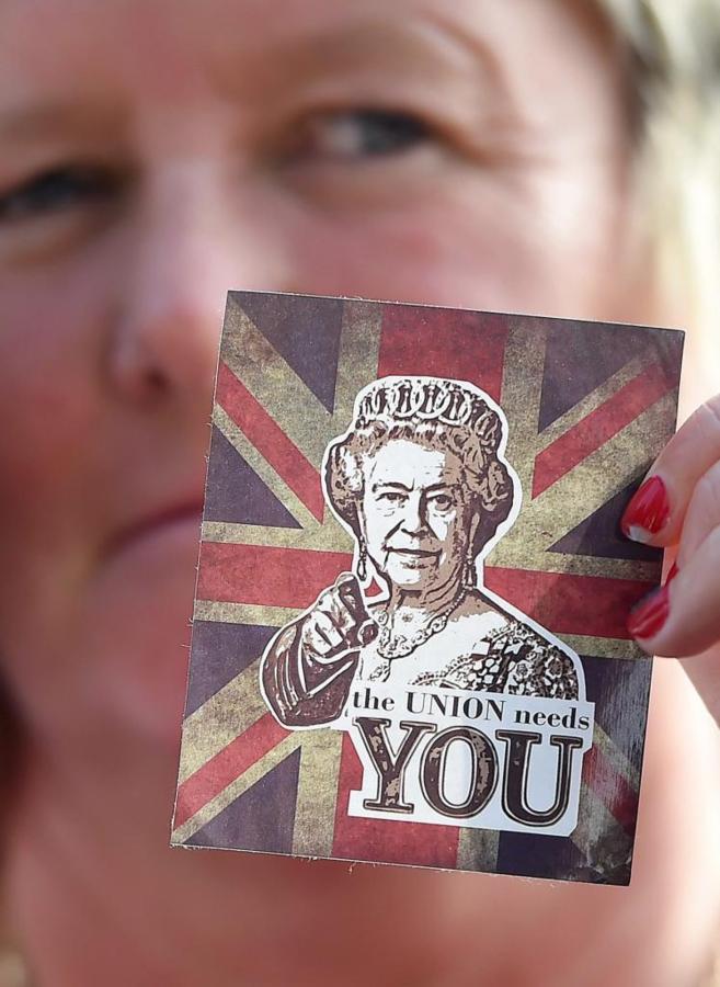 Una simpatizante anti-independentista muestra una estampa de la reina...