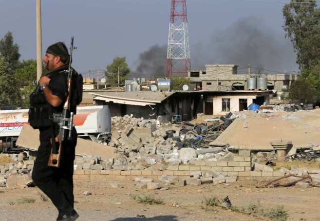 Un luchador 'peshmerga' camina junto a una casa destruida en...