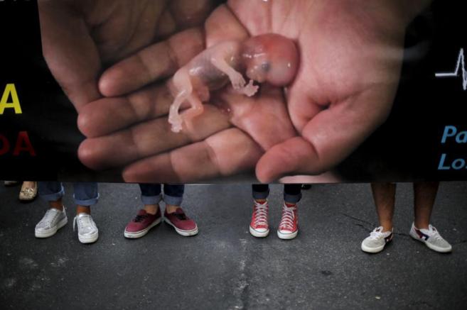 Cartel donde una mano sostiene un feto