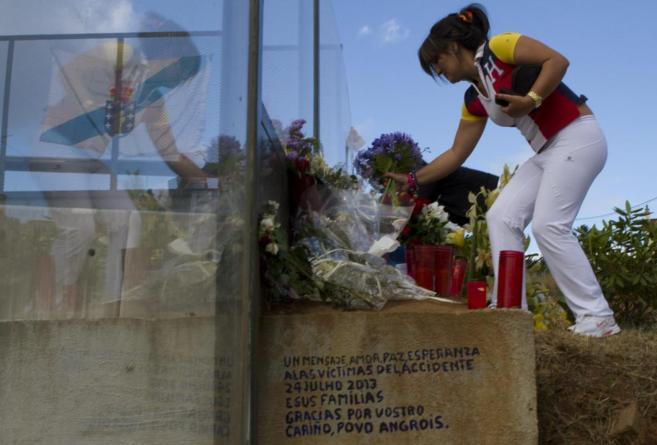 Una mujer deposita un ramo de flores en el lugar del accidente.