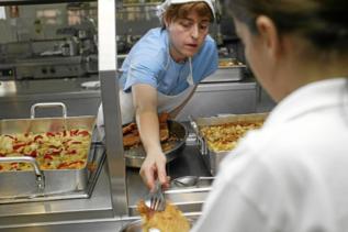 Una trabajadora reparte la comida a una alumna de un colegio de...