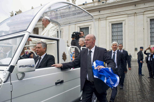 Un guardia de seguridad del Papa Francisco portando una bandera del...