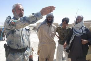 Un militar afgano habla con vecinos afectados.
