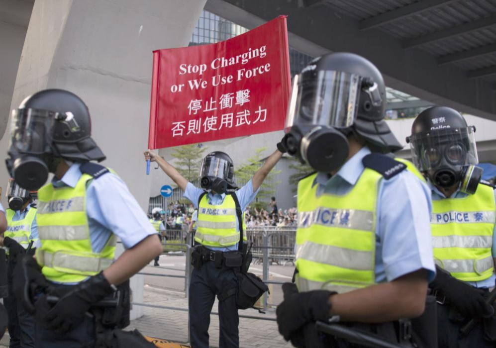Un polica porta una pancarta en la que se puede leer: "Dejen de...
