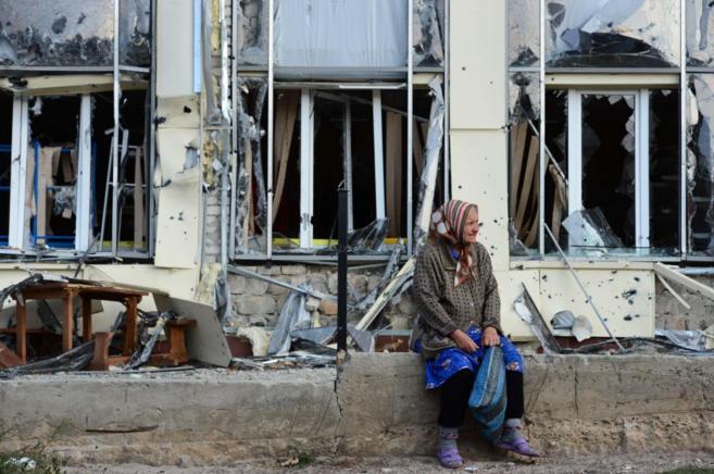 Una anciana descansa en un edificio devastado en Pervomaisk, a 50...
