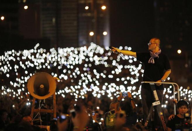 MIles de hongkoneses iluminan a la vez sus teléfonos móviles en...