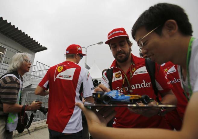 Fernando Alonso, junto a su compaero Kimi Raikkonen, a su llegada al...