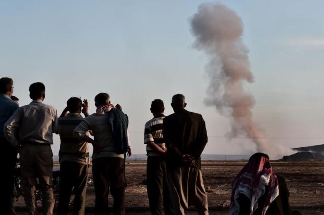 Un grupo de kurdos observa el bombardeo aliado de las posiciones...