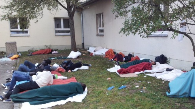 Un grupo de refugiados duerme a la intemperie en los jardines de un...