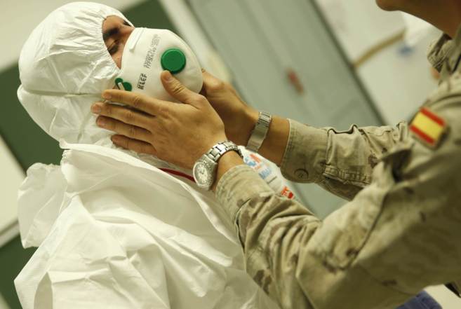 Un militar ensea a un miembro del personal sanitario a colocarse el...