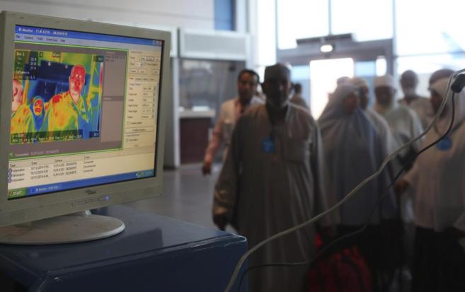 Trabajadores sanitarios usan un escáner con infrarrojos para medir la...
