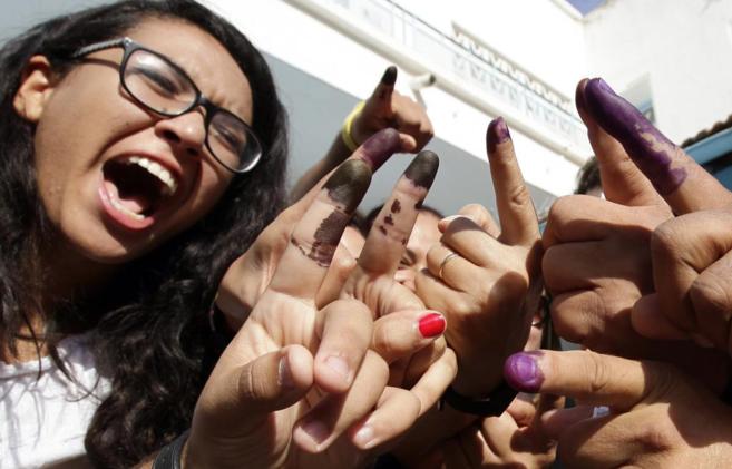 Votantes tunecinos enseñan sus dedos manchados de tinta tras votar en...