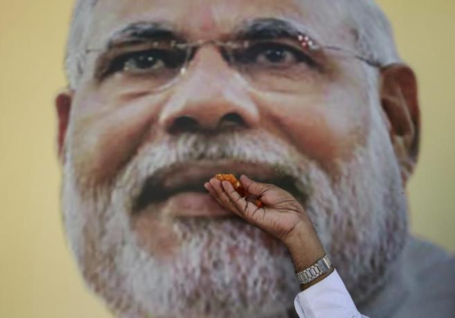 Un seguidor de primer ministro Modi posa con caramelos ante un cartel...