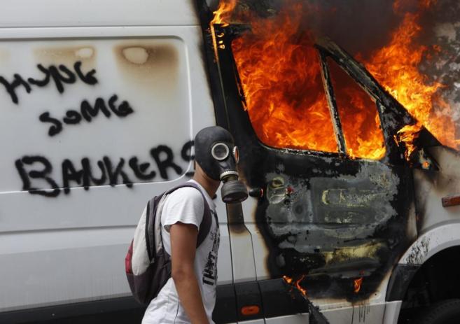 Un joven  pasa junto a un coche ardiendo durante las violentas...