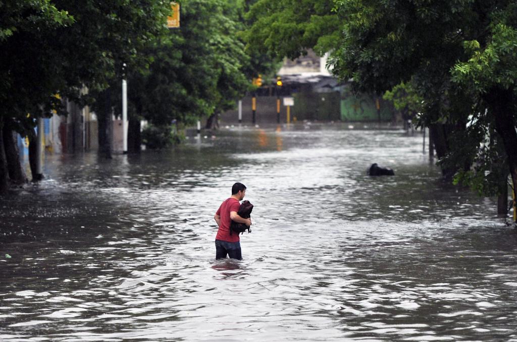 Una persona trata de cruzar una calle inundada. | Internacional | EL MUNDO