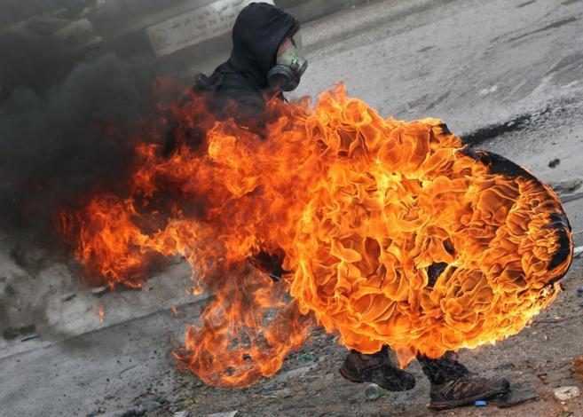 Un manifestante palestino lanza un neumtico en llamas en un choque...
