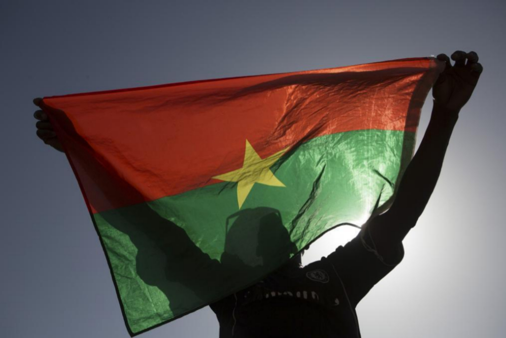 Un manifestante pro-democracia sostiene una bandera de Burkina Faso en...