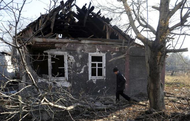 Un lugareo camina frente a su casa, destruida durante un bombardeo...