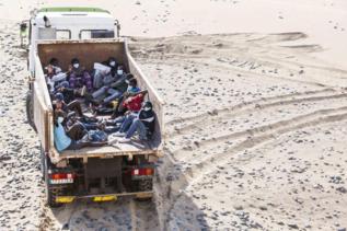 Los inmigrantes subidos en un camin de limpieza en la playa de...