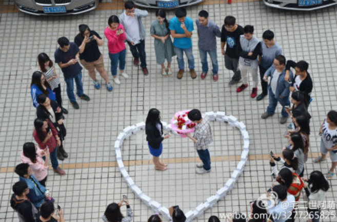El joven chino, mientras peda matrimonio a su pareja, rodeado de...