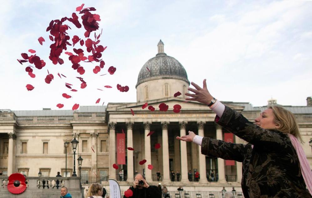 Una mujer lanza amapolas al aire en Trafalgar Square como gesto a los...