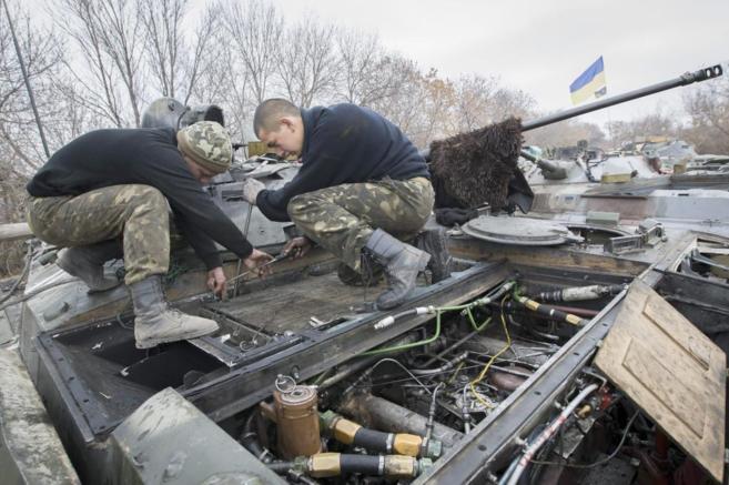 Dos uniformados ucranianos revisan un blindado en las cercanas de...