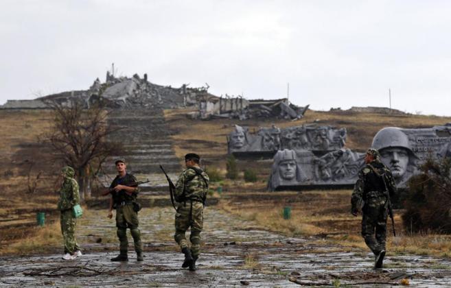 Separatistas prorrusos caminan hacia un memorial de guerra destruido...