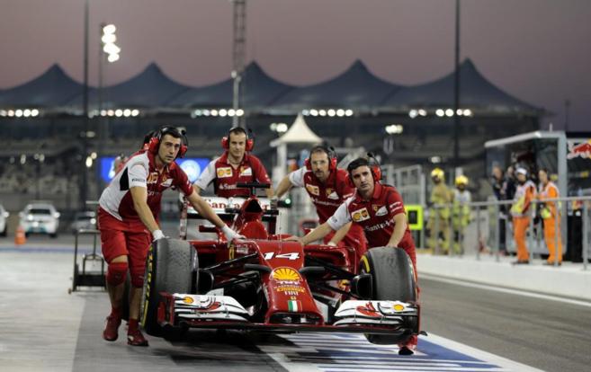 Los mecnicos de Ferrari llevan el coche de Fernando Alonso al...