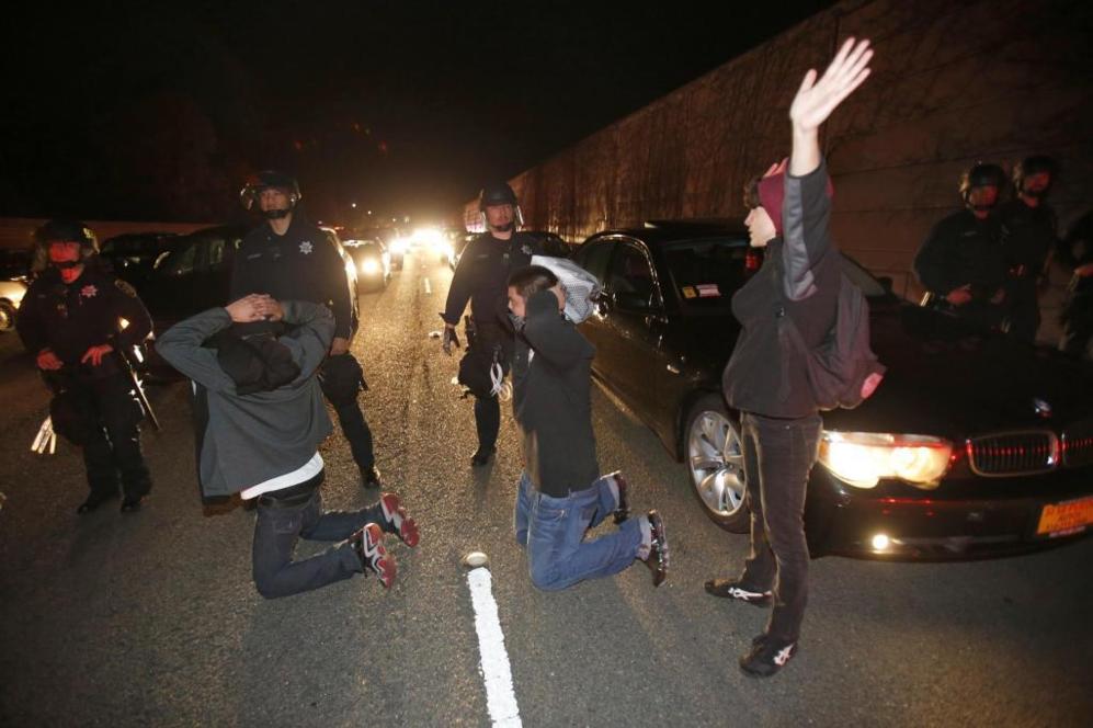 Ciudadanos protestan de rodillas frente a la polica en Oakland,...