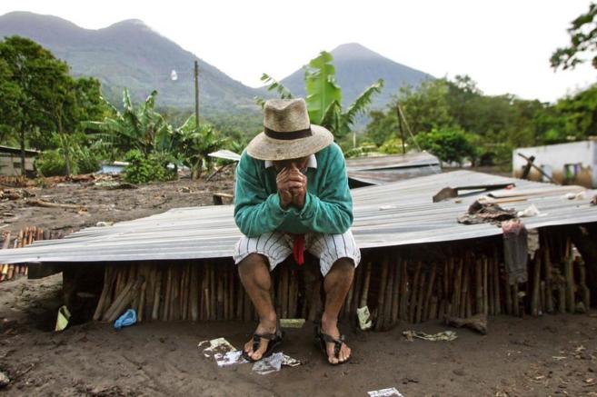 Un indgena de un poblado de Guatemala, sentado sobre lo que fue su...