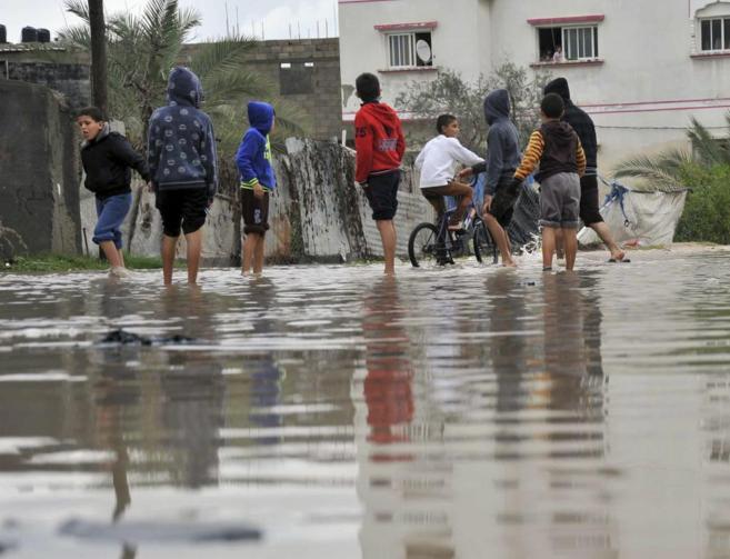 Nios palestinos juegan en una calle completamente inundada.