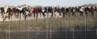 Un grupo de inmigrantes subsaharianos encaramados en la valla de...