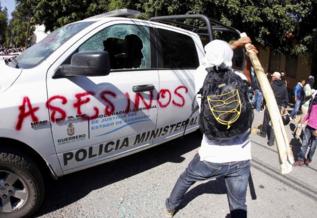 Un manifestante golpea un coche policial en Chilpancingo.