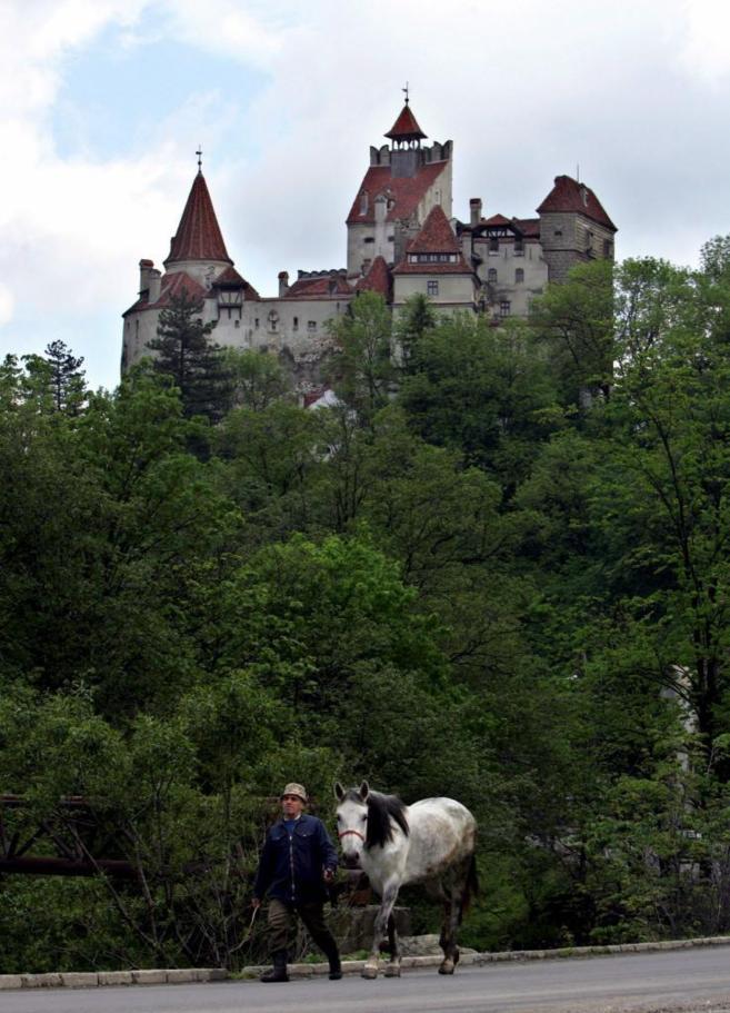 Un hombre con un caballo pasea delante de un castillo