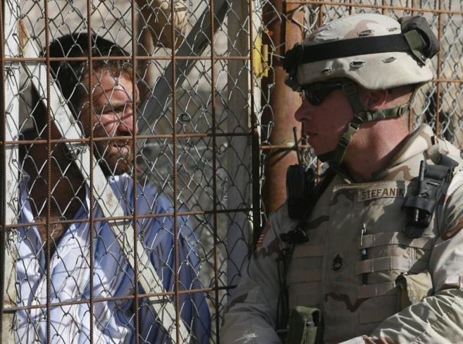 Un soldado estadounidense y un preso iraqu se observan en la...