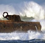 Una ola rompe junto a la escultura el 'Peine del Viento' en San...
