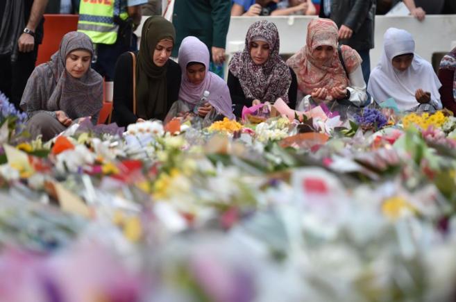 Jvenes musulmanas rezan frente a las flores colocadas en honor de...