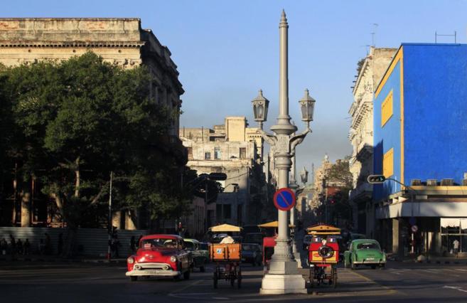 Ciclotaxis y vehculos en una calle de La Habana vieja.
