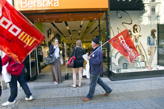 Unos sindicalistas pasan por delante de una tienda en plena protesta.