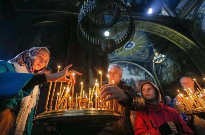 Ucranianos encienden verlas durante una misa ortodoxa de Semana Santa...