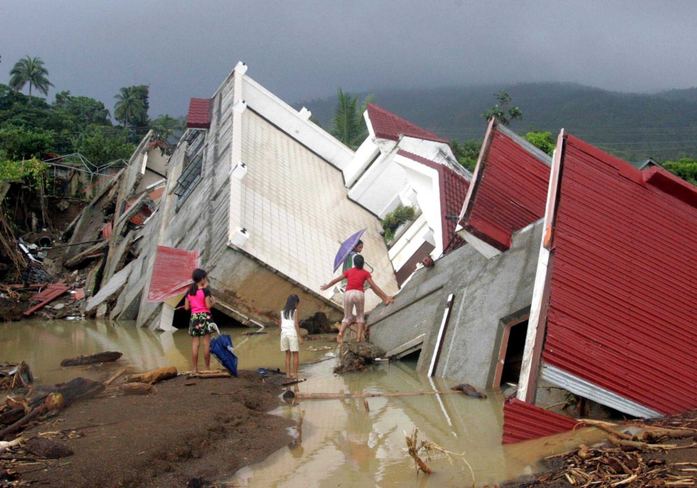 Nios filipinos juegan cerca de una casa destruida por los...