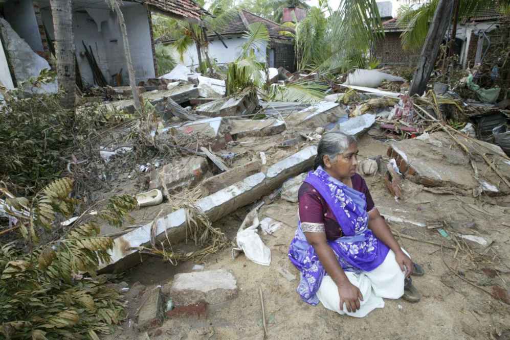 Mujer de Sri Lanka se sienta delante de su casa destruida en Kalmuni.