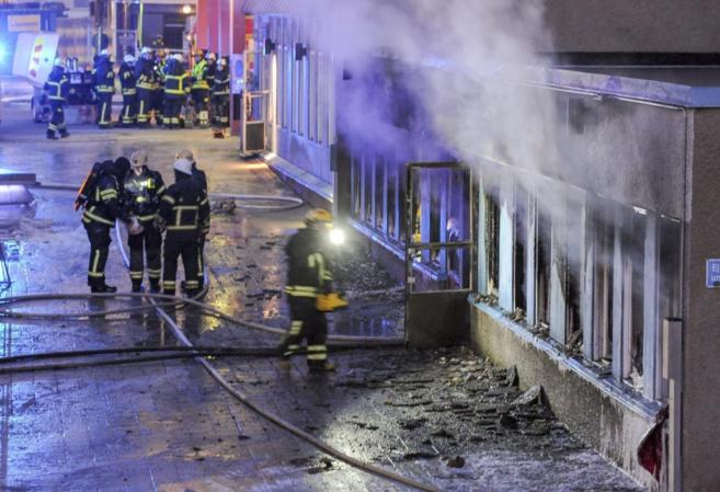 Varios bomberos apagan los restos del incendio en el stano de una...