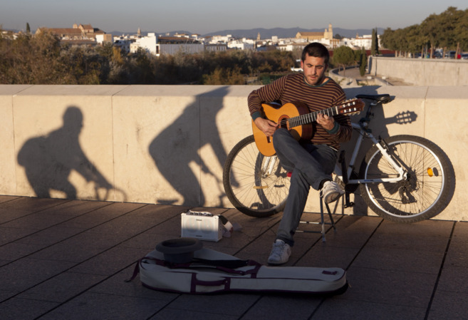 Un músico toca en el Puente Romano de Córdoba.